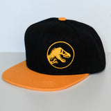 Black and yellow Jurassic Snapback with dinosaur logo on a light gray background