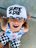 Child wearing a 'Skate or Die' snapback with a checkered outfit.