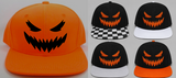 Five pumpkin-themed snapback caps shown on a light gray background, including one large orange cap with a black jack-o'-lantern face and four smaller black caps with orange faces and different brim designs.